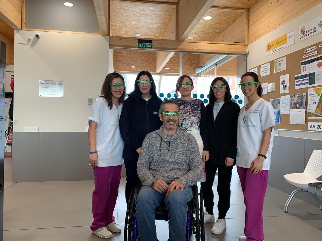 Miembros de ASPAYM Castilla y León en Ávila posan con las gafas verdes de la campaña "Mira por la discapacidad"