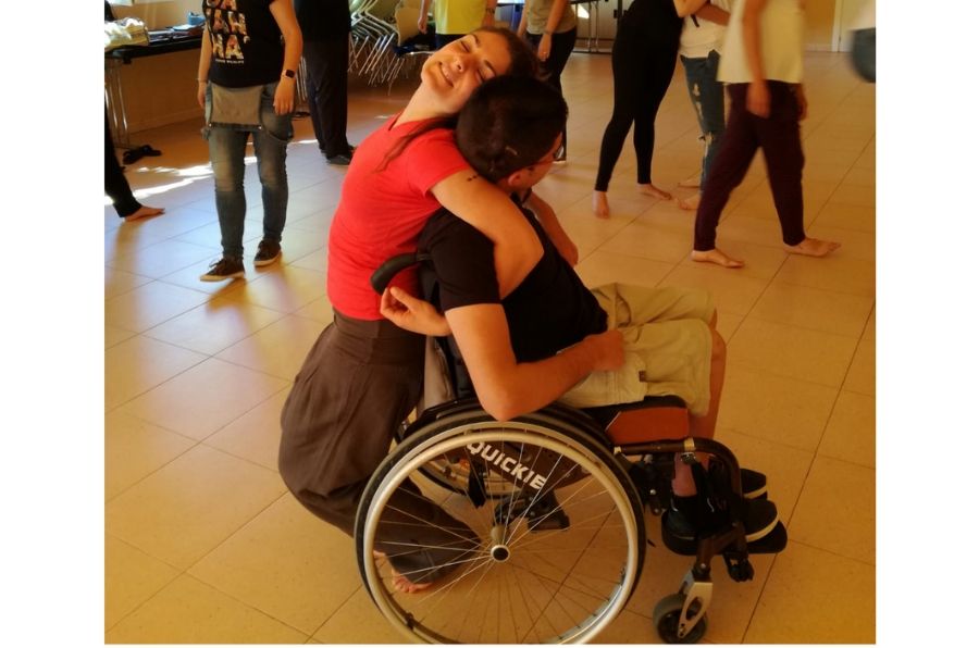 Una joven sin discapacidad y un joven con discapacidad se entrelazan en un baile