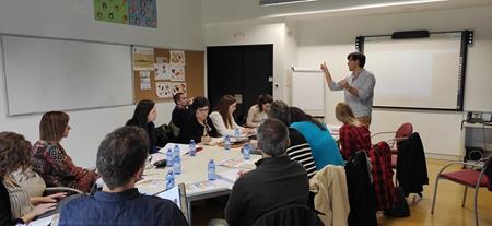 Fotografía de los asistentes a la reunión en una mesa atendiendo a una explicación del coordinador