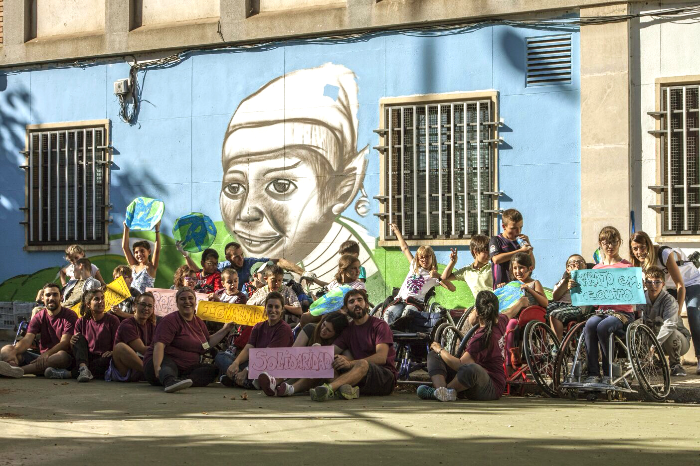 Fotografía de un grupo de juventud de ASPAYM Burgos, al lado de una fachada decorada con un bonito mural