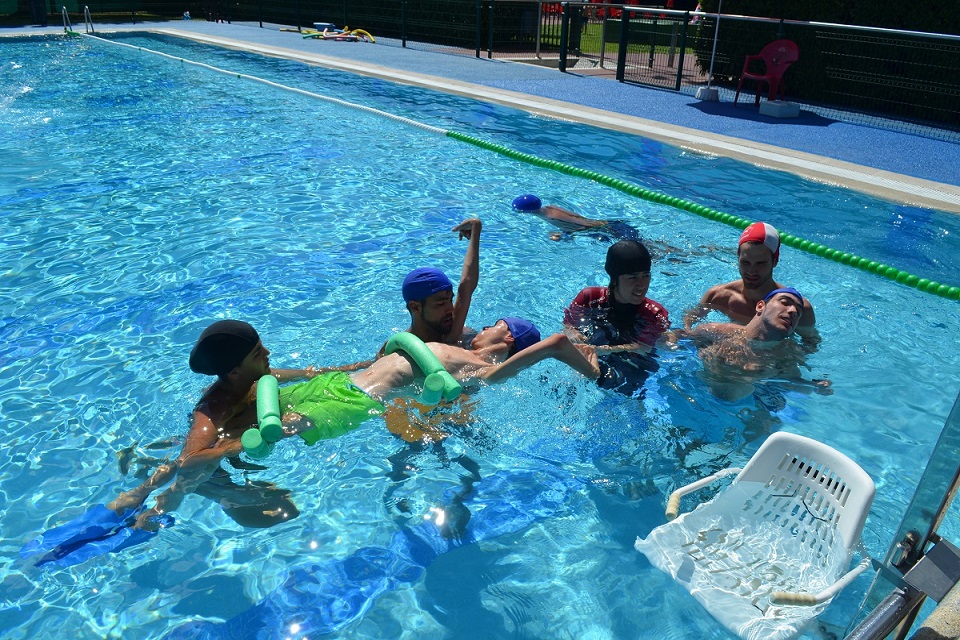 Jóvenes ayudando a personas con discapacidad a bañarse en la piscina