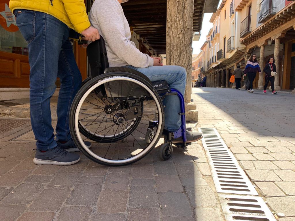 Asistente Personal hace turismo con persona en silla de ruedas por un pueblo de la comunidad