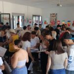 Grupo numeroso de jóvenes de distintos países participando en una dinámica en una sala de Valladolid, con banderas internacionales colgadas al fondo y documentos en las manos